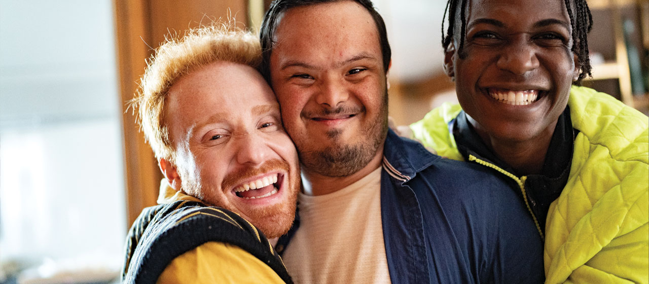 three males hugging and smiling